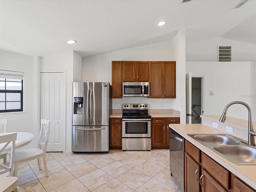 A kitchen features wood cabinets, stainless steel appliances, and tile flooring — 630 VALENCIA COURT, DUNDEE, FL