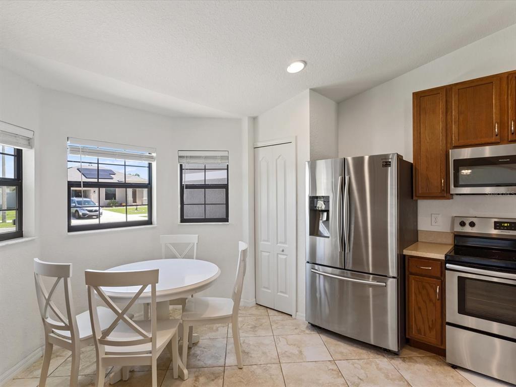A kitchen with a dining area, stainless steel appliances, wood cabinets, and tile flooring — 630 VALENCIA COURT, DUNDEE, FL