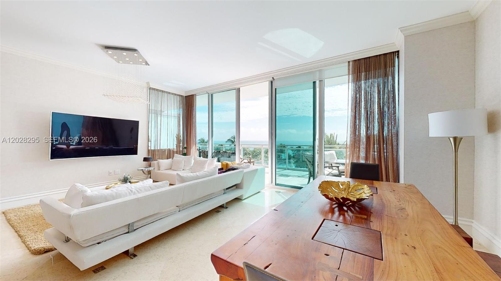 A bright living and dining area features white sofas, a wooden table, and balcony views — 10295 Collins Ave # 205, Bal Harbour FL 33154, BAL HARBOUR, FL
