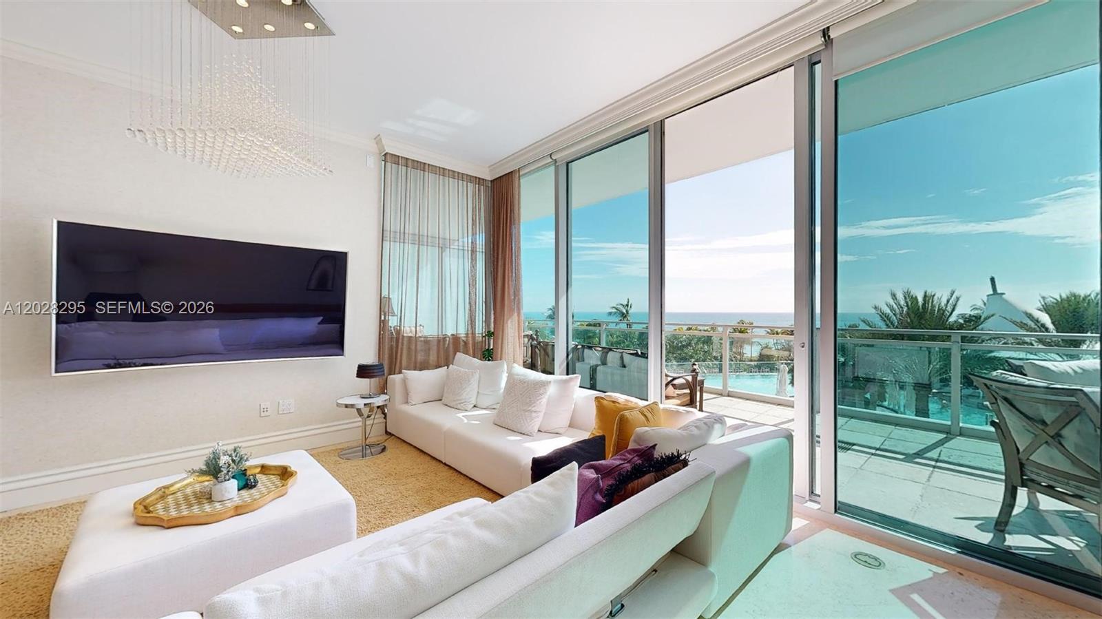 A bright living room features a white sectional sofa, a large television, and floor-to-ceiling windows — 10295 Collins Ave # 205, Bal Harbour FL 33154, BAL HARBOUR, FL
