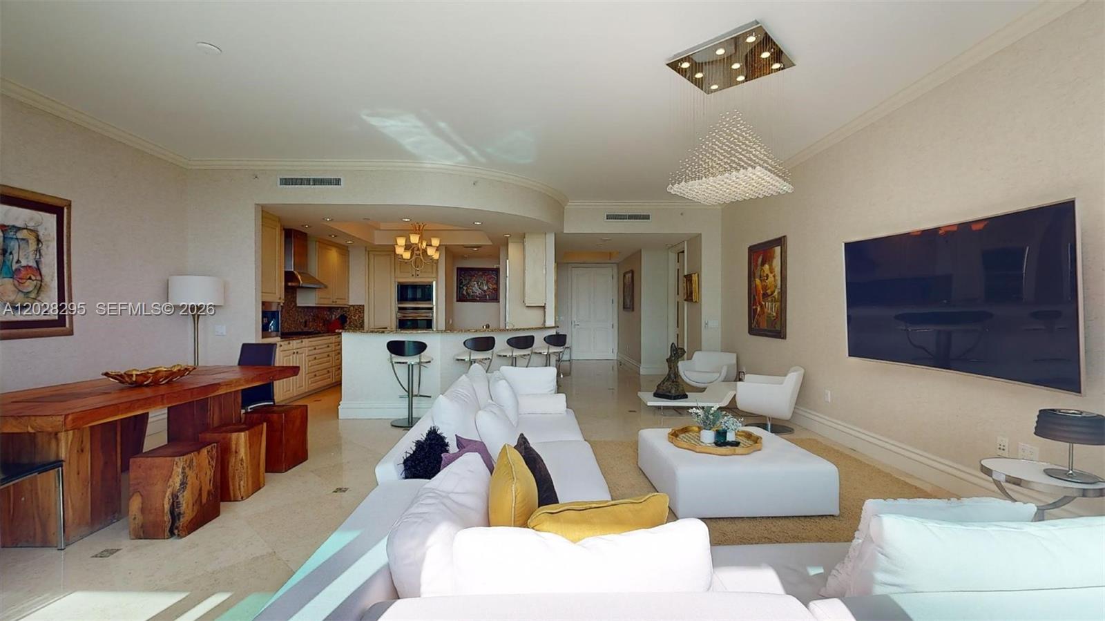 A spacious living room features a white sectional sofa, a large television, and an open kitchen — 10295 Collins Ave # 205, Bal Harbour FL 33154, BAL HARBOUR, FL