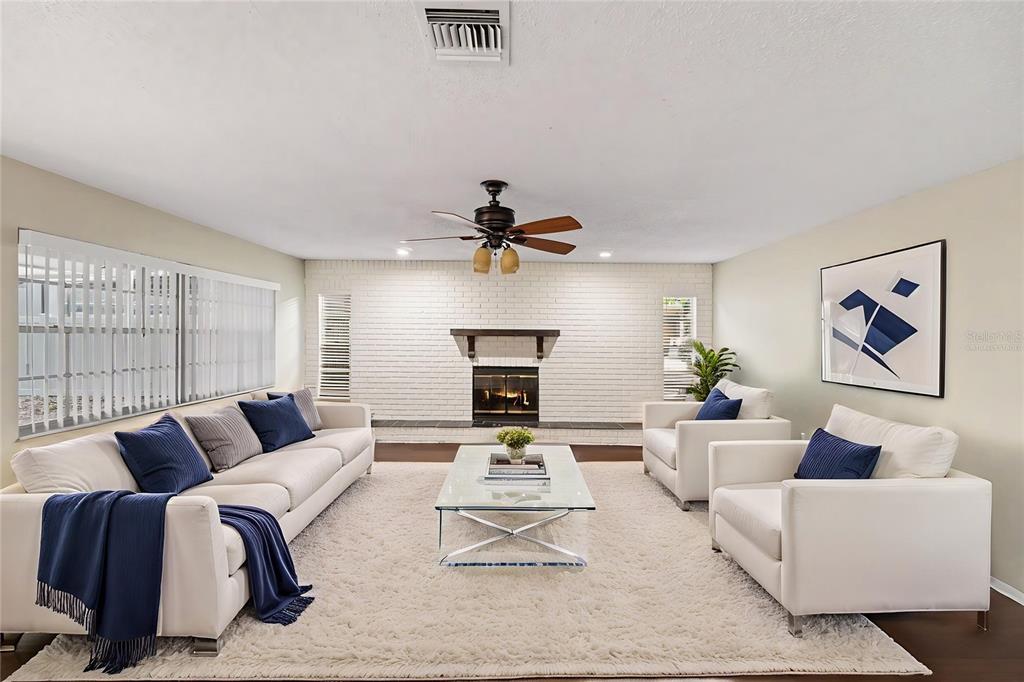 A living room features a white brick fireplace, a glass coffee table, and white furniture — 2431 GROVE RIDGE DRIVE, PALM HARBOR, FL