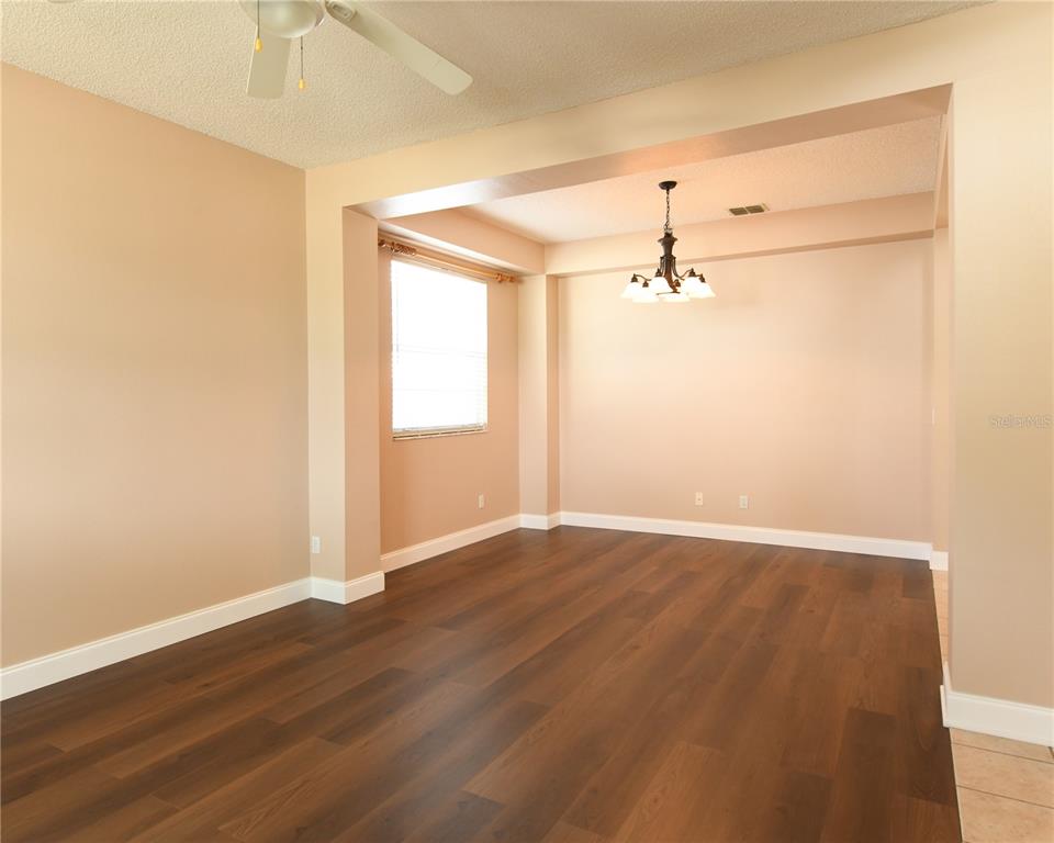 An empty dining room with dark wood flooring, beige walls, and a hanging light fixture — 812 JADE FOREST AVENUE, ORLANDO, FL
