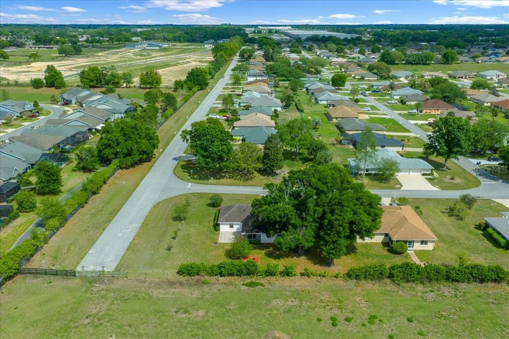 An aerial view shows a residential street lined with houses, trees, and grassy lots — 3498 NW 50TH COURT, OCALA, FL