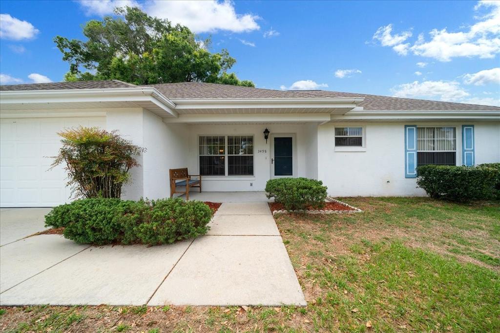 A single-story white house with a concrete walkway, a garage, and a front porch — 3498 NW 50TH COURT, OCALA, FL