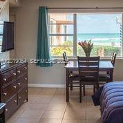 A bedroom features a wooden dresser, a dining set, and a large window overlooking the ocean — 0 N Surf Rd, Hollywood FL 33019, HOLLYWOOD, FL