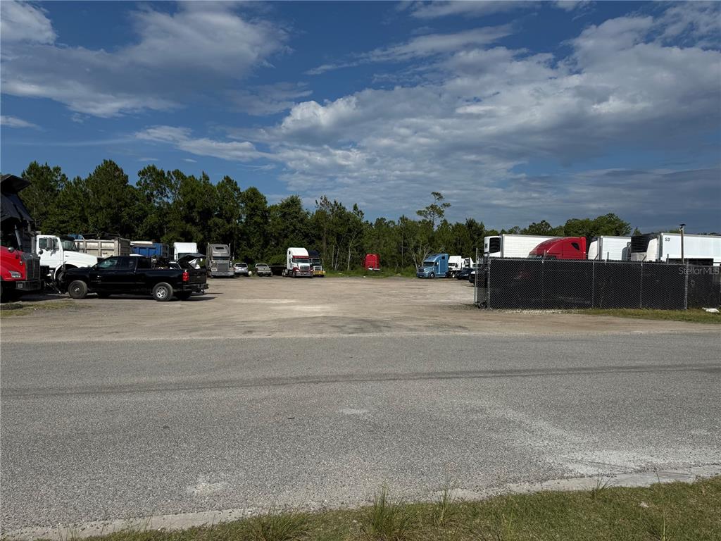 A gravel lot contains several parked semi-trucks and trailers behind a chain-link fence — 3330 STEEL RAIL DR DRIVE UNIT 1, BUNNELL, FL