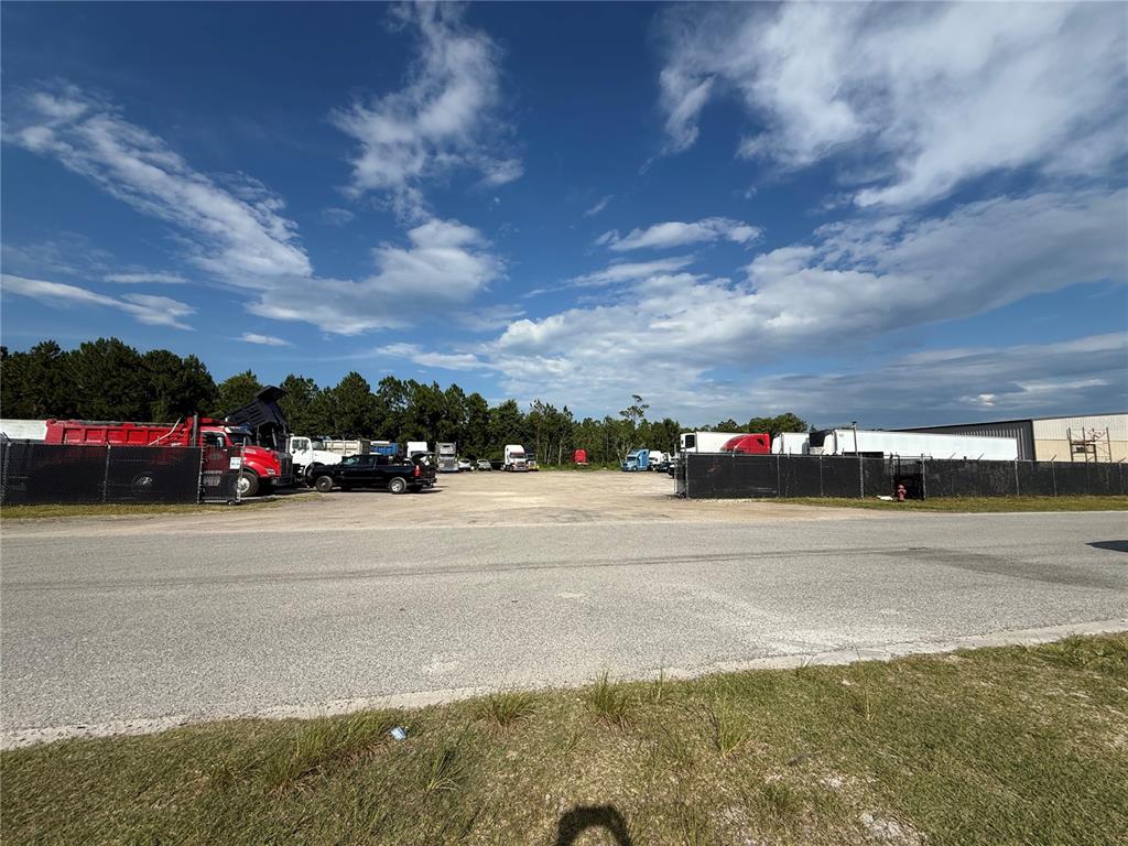 A gravel lot with parked semi-trucks and trailers is enclosed by a chain-link fence — 3330 STEEL RAIL DR DRIVE UNIT 1, BUNNELL, FL