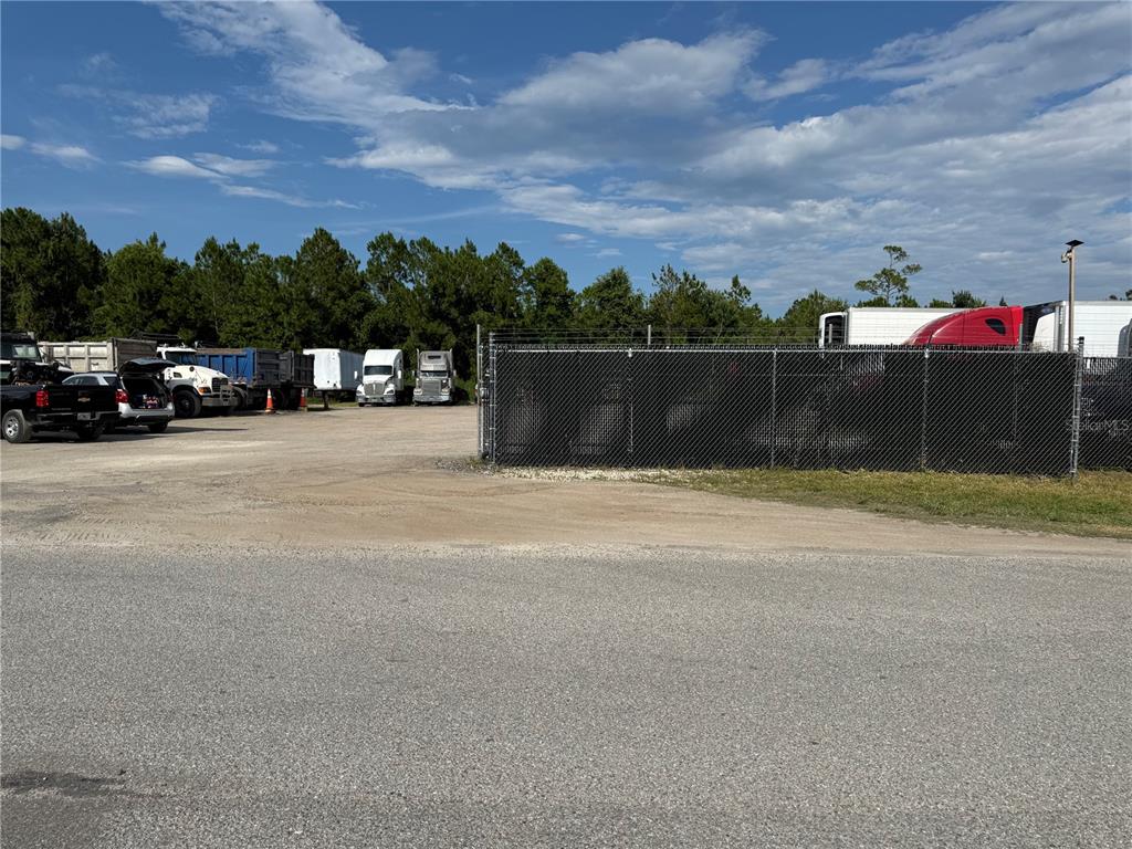 A gravel lot contains several parked semi-trucks and trailers behind a chain-link fence — 3330 STEEL RAIL DR DRIVE UNIT 1, BUNNELL, FL