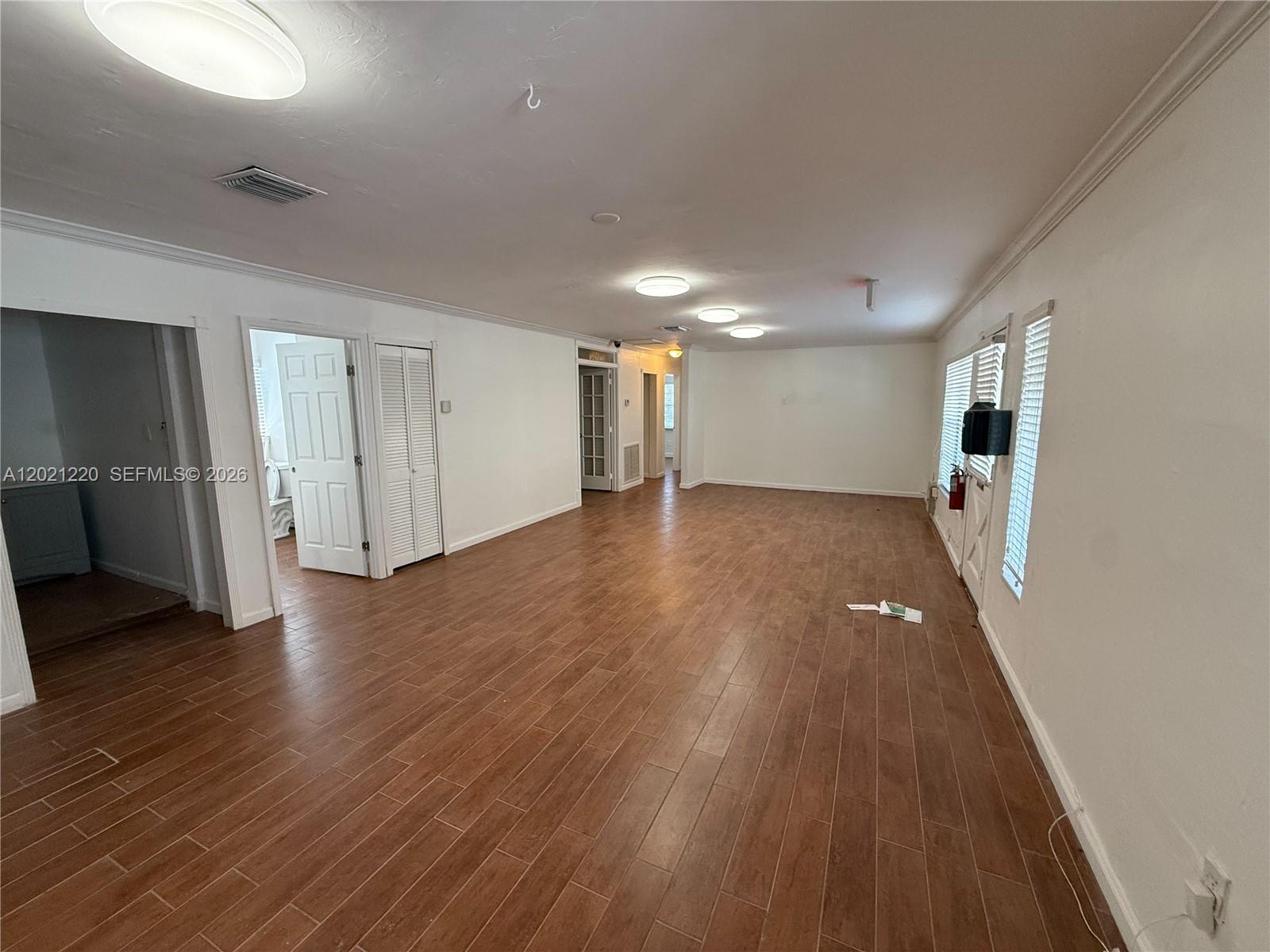 An empty room features wood-look tile flooring, white walls, and multiple ceiling lights — 5935 Taft St, Hollywood FL 33021, HOLLYWOOD, FL