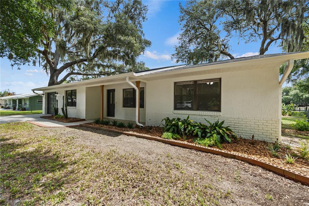 A single-story white brick house with a covered entryway and large shade trees — 2457 S SUMMERWOOD POINT, INVERNESS, FL