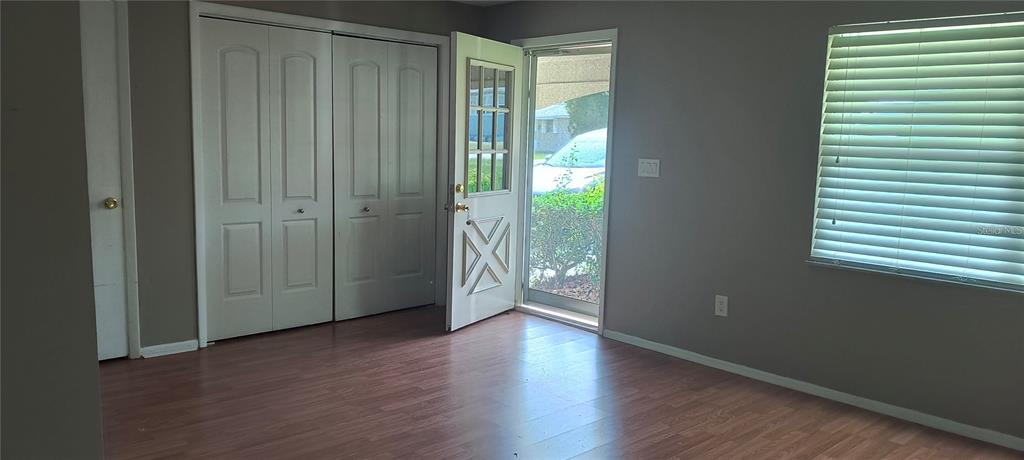 A room with wood-look flooring, gray walls, a white closet, and an open front door — 14560 SW 35TH TERRACE ROAD, OCALA, FL