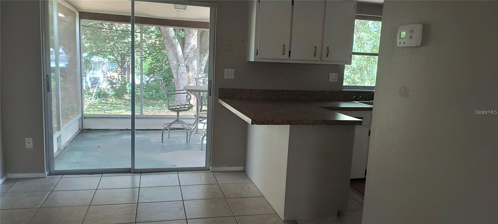 A kitchen with a breakfast bar and tile flooring opens to a screened-in patio — 14560 SW 35TH TERRACE ROAD, OCALA, FL