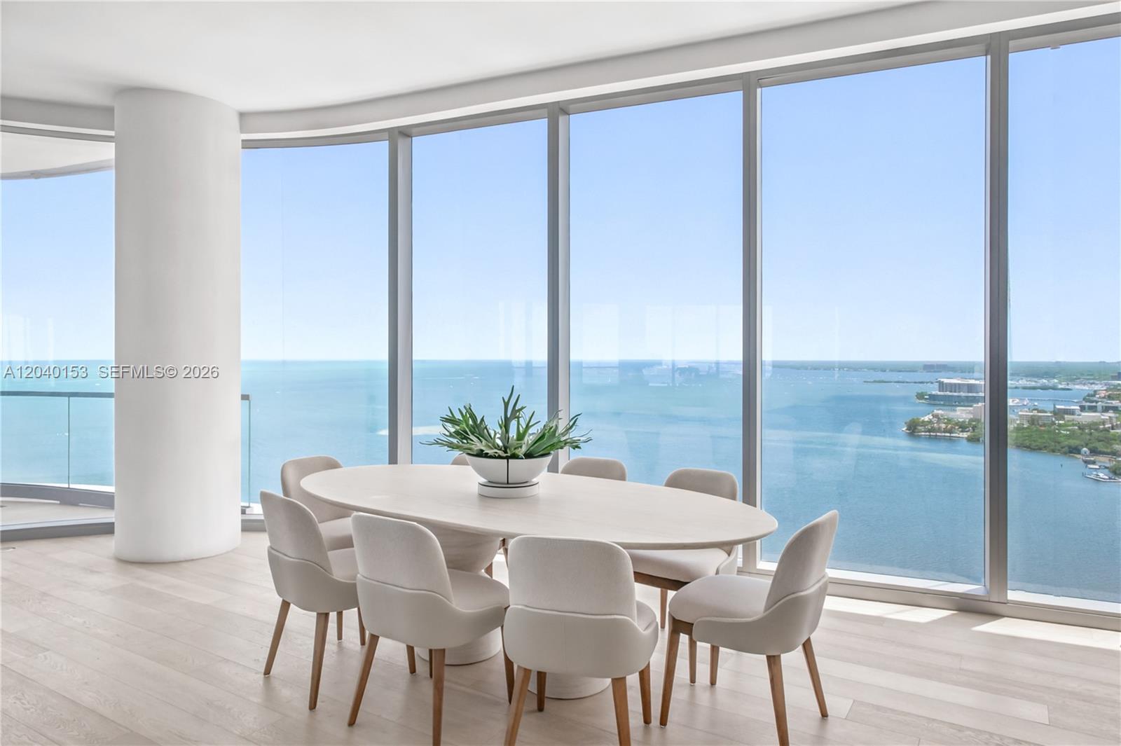 A dining room features an oval table, six chairs, and floor-to-ceiling windows overlooking water — 175 SE 25th., Miami FL 33129, MIAMI, FL