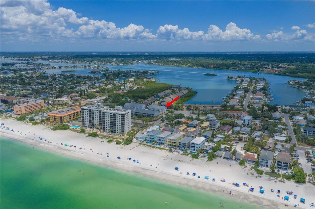 An aerial view shows a coastal beach town with a red arrow pointing to a building — 901 HARBOUR HOUSE DRIVE, INDIAN ROCKS BEACH, FL