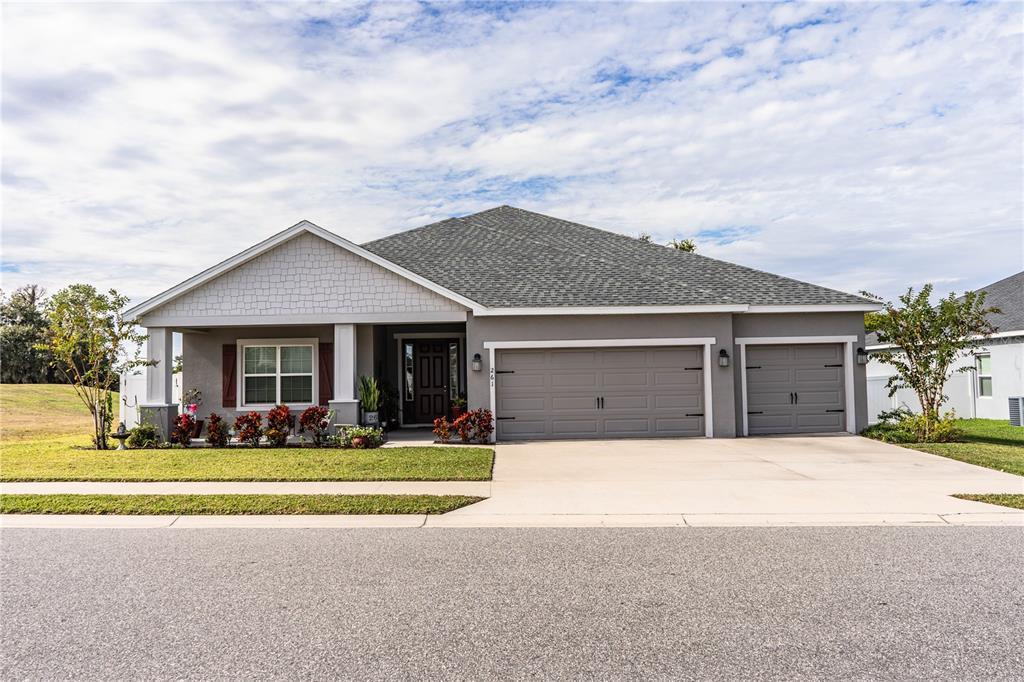 A single-story gray house with a three-car garage and a front porch — 261 WALKERS POINT DRIVE, AUBURNDALE, FL