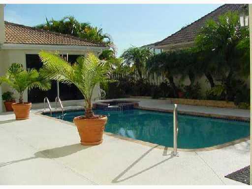 A swimming pool with a hot tub sits on a patio beside a residential home — 9067 Long Lake Palm Drive, Boca Raton FL 33496, BOCA RATON, FL