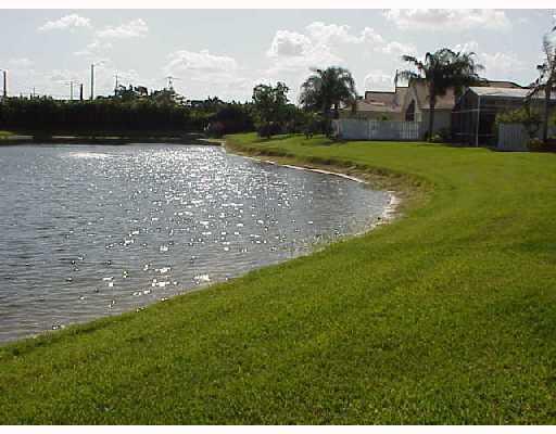 A grassy lawn slopes down to a pond behind a row of suburban houses — 9067 Long Lake Palm Drive, Boca Raton FL 33496, BOCA RATON, FL