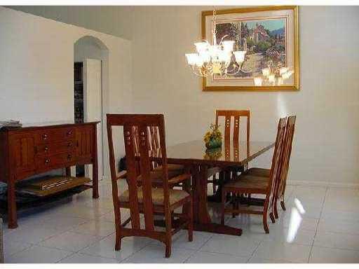 A dining room features a wooden table and chairs, a sideboard, and a crystal chandelier — 9067 Long Lake Palm Drive, Boca Raton FL 33496, BOCA RATON, FL