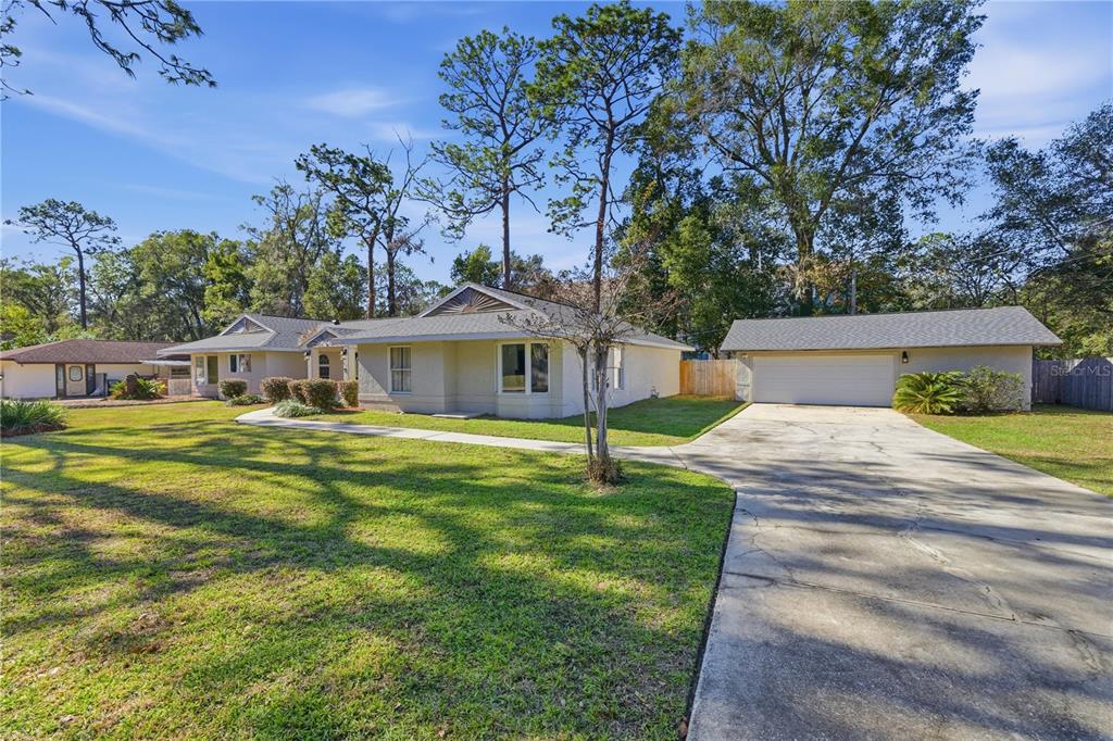 A single-story house with a light-colored exterior, a detached garage, and a concrete driveway — 1408 NE 42ND AVENUE, OCALA, FL