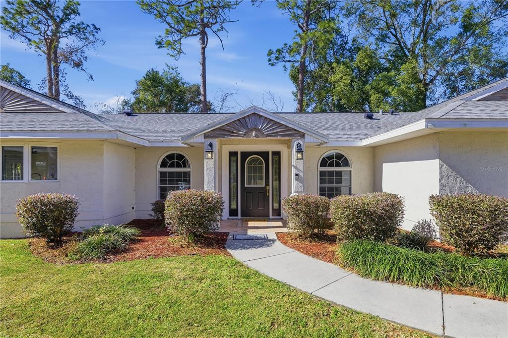 A single-story house with a white stucco exterior, arched windows, and a central front entrance — 1408 NE 42ND AVENUE, OCALA, FL