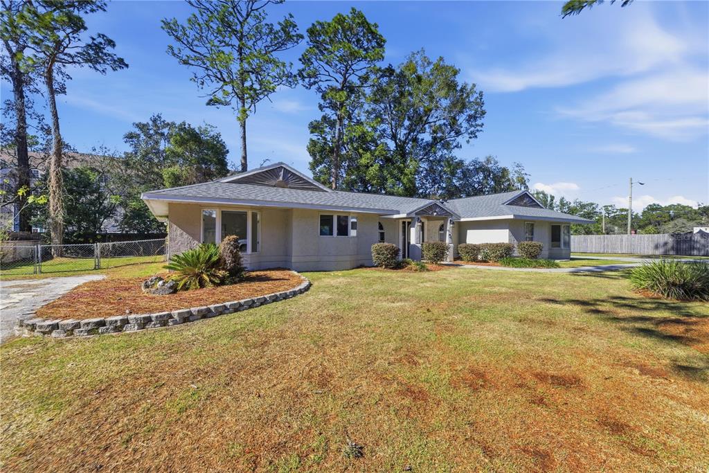 A single-story house with a light-colored stucco exterior and a gray shingled roof — 1408 NE 42ND AVENUE, OCALA, FL