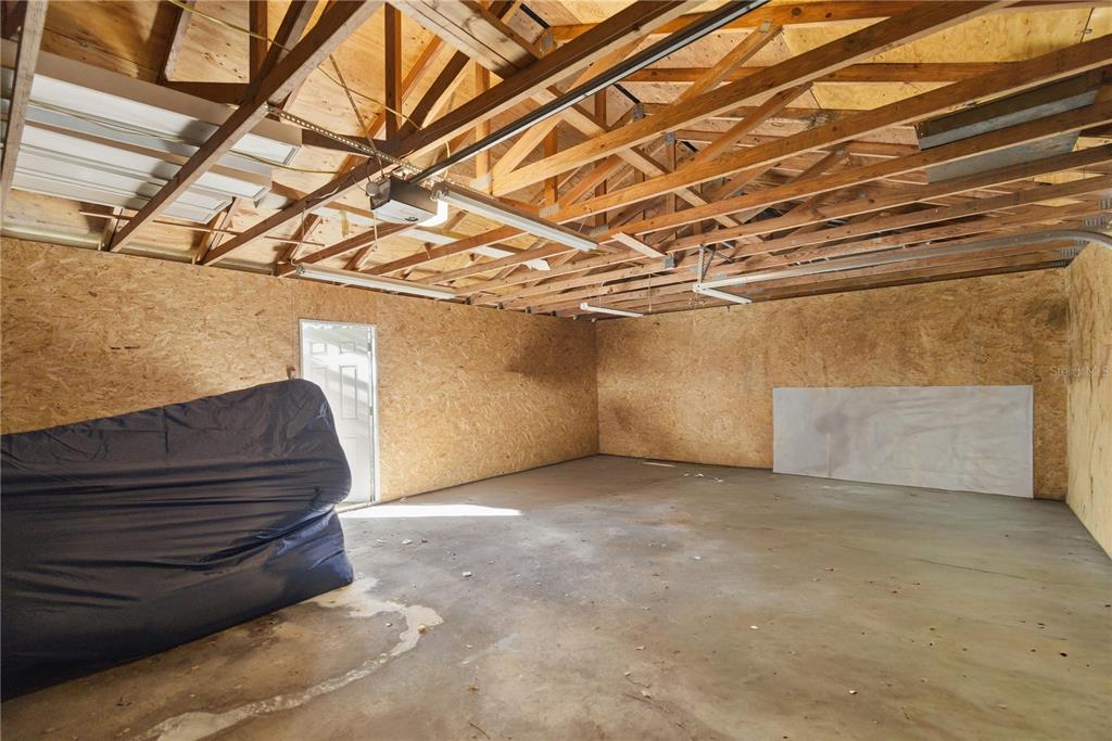 An unfinished garage with exposed wood trusses, OSB walls, and a concrete floor — 1408 NE 42ND AVENUE, OCALA, FL