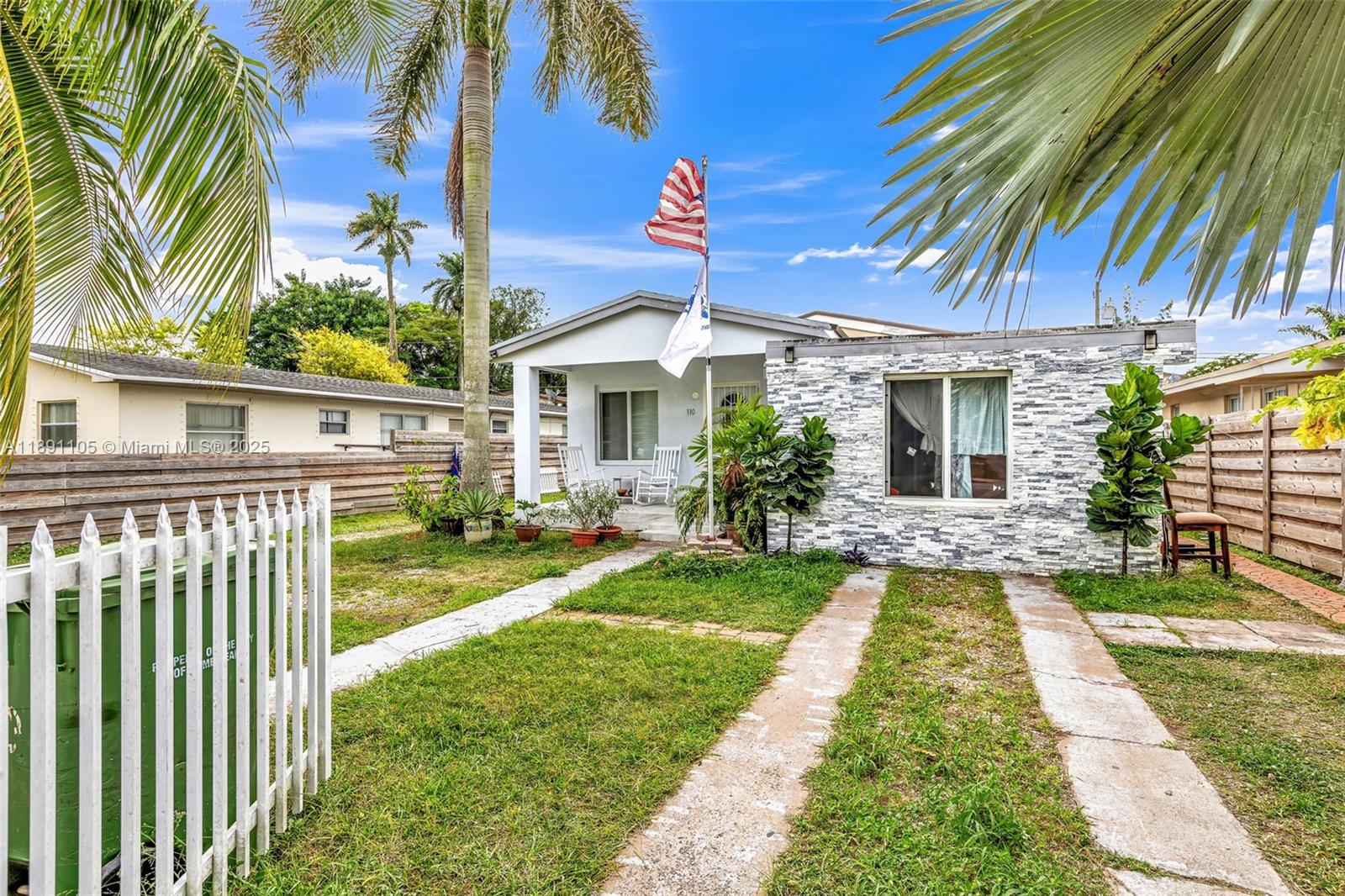 A single-story house with a stone-veneer facade, a front yard, and a white picket fence — 110 NE 9th Ct, Homestead FL 33030, HOMESTEAD, FL