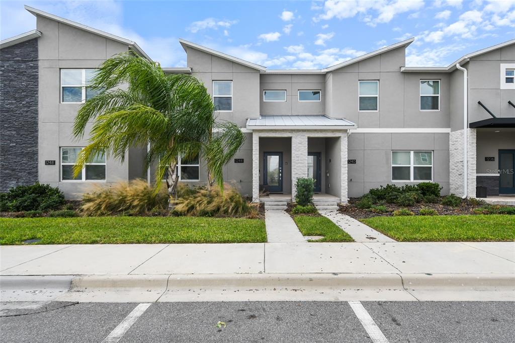 A row of modern two-story townhomes with gray stucco facades and stone accents — 1244 CHALLENGE DRIVE, DAVENPORT, FL