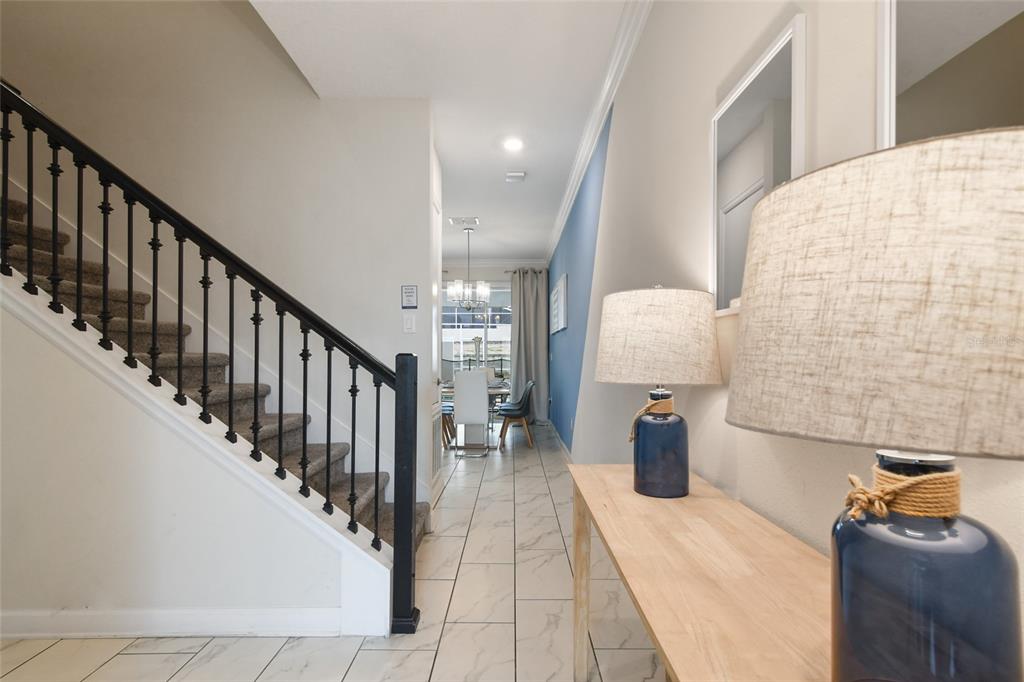 A hallway with a staircase, tile flooring, and a console table with blue lamps — 1244 CHALLENGE DRIVE, DAVENPORT, FL