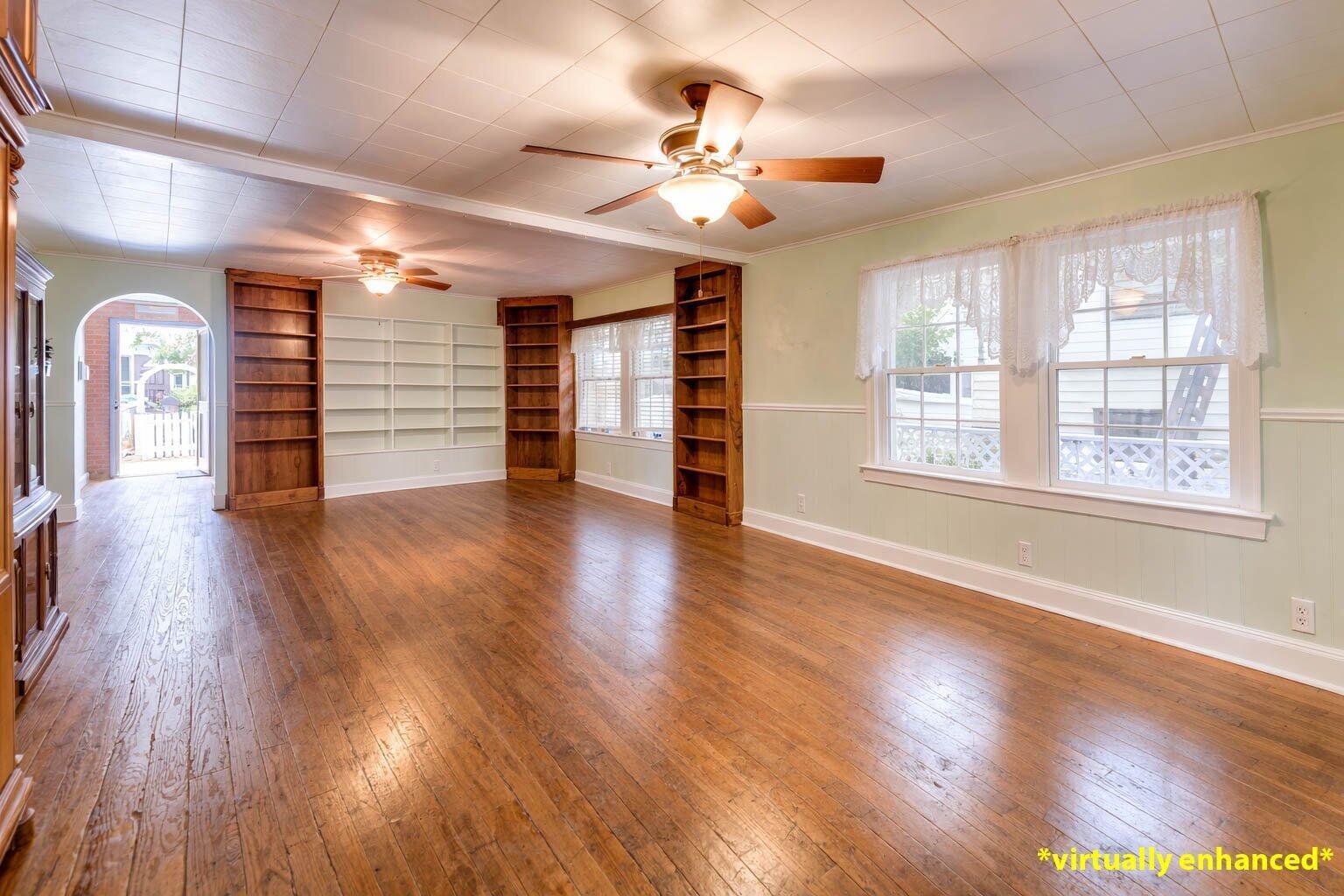 A spacious living room features hardwood floors, built-in wooden bookshelves, and light green walls — 1425 Eliza Street, Key West FL 33040, KEY WEST, FL