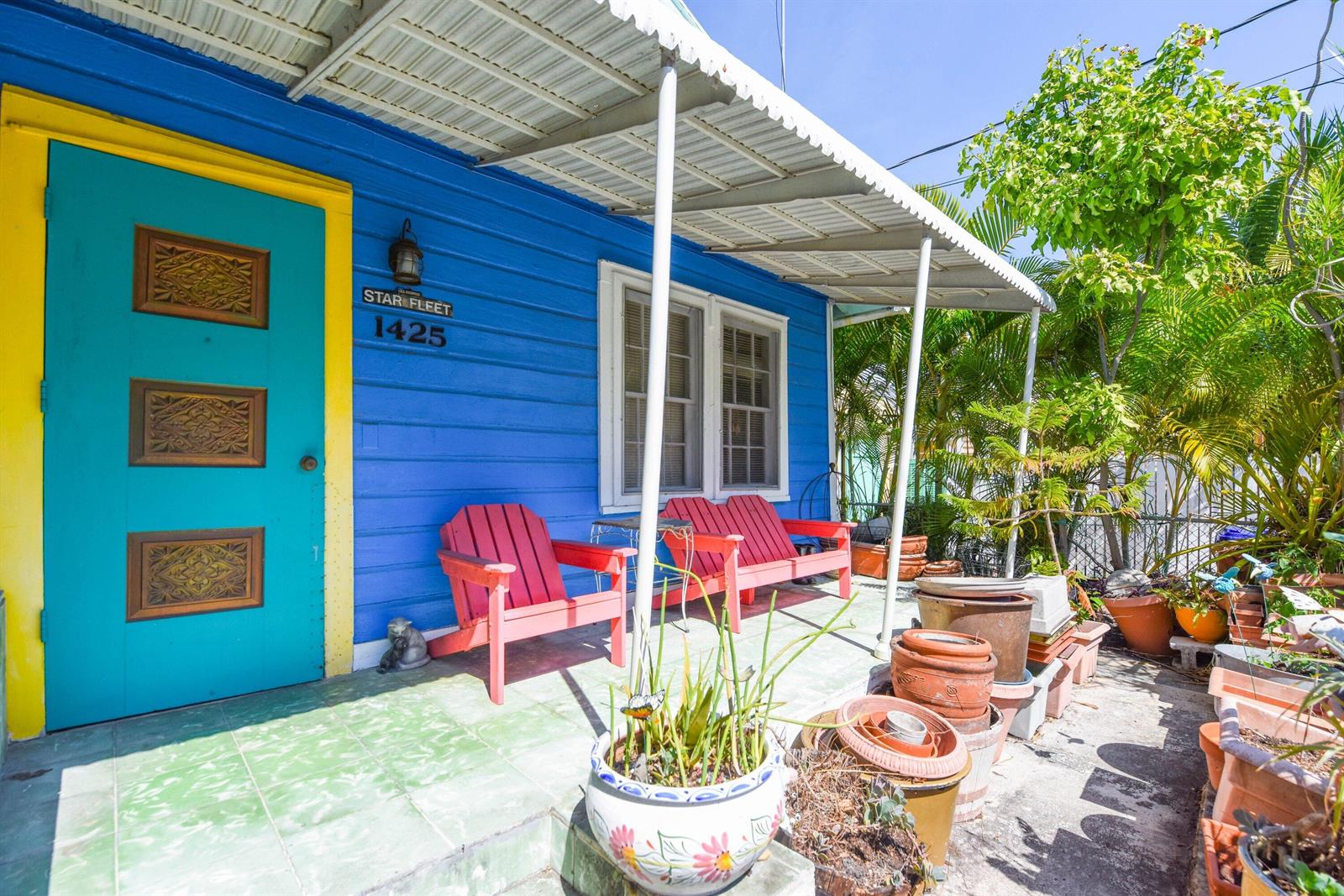 A blue house exterior features a bright turquoise door, red chairs, and many potted plants — 1425 Eliza Street, Key West FL 33040, KEY WEST, FL