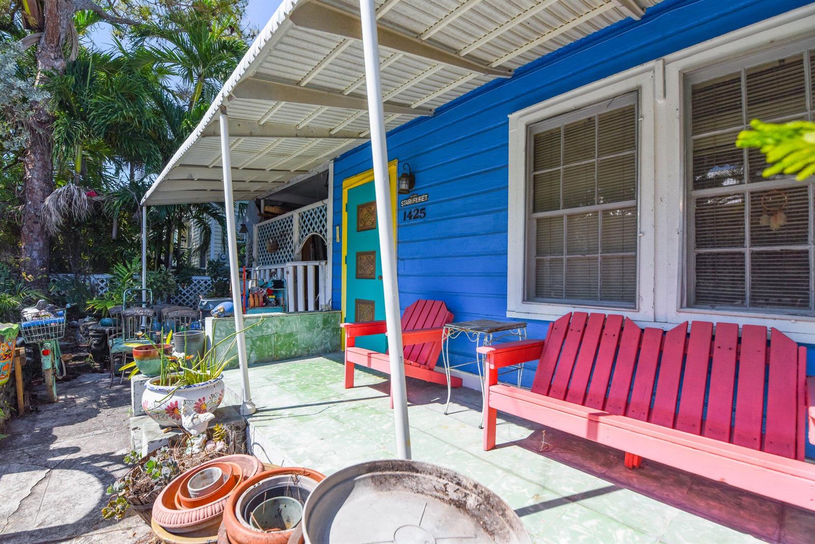 A bright blue house exterior features a covered porch with red benches and potted plants — 1425 Eliza Street, Key West FL 33040, KEY WEST, FL