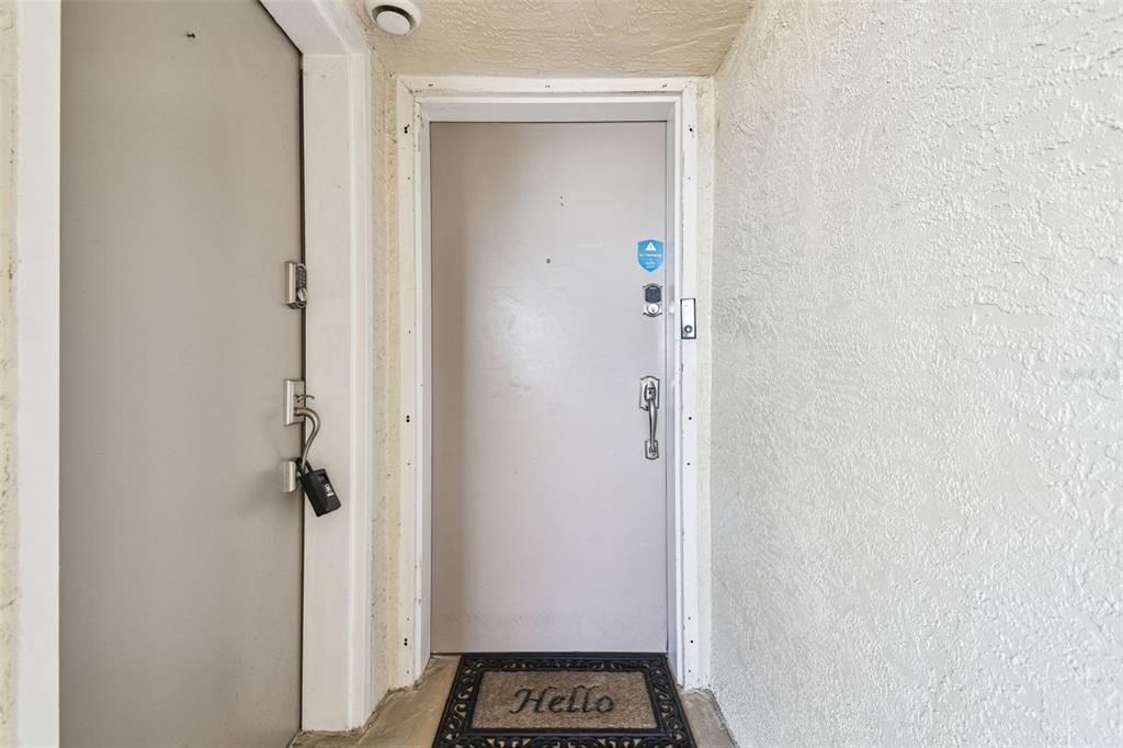 A gray front door with a lockbox and a welcome mat in a recessed entryway — 5915 SEA RANCH DRIVE UNIT 108, HUDSON, FL