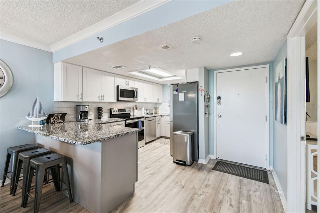A kitchen features white cabinets, granite countertops, stainless steel appliances, and a breakfast bar — 5915 SEA RANCH DRIVE UNIT 108, HUDSON, FL