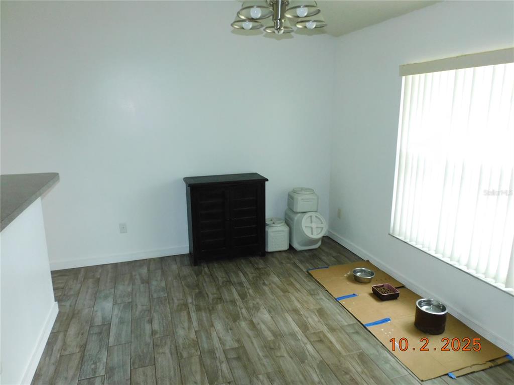 A dining area features wood-look tile flooring, a dark storage cabinet, and a window with blinds — 2542 CAMPHORWOOD CIRCLE, KISSIMMEE, FL