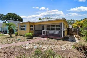 A yellow single-story house features a front porch with a lattice railing and a metal roof — 144 30TH AVENUE N, ST PETERSBURG, FL