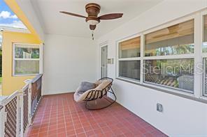 A covered patio features red tile flooring, a ceiling fan, and a single rocking chair — 144 30TH AVENUE N, ST PETERSBURG, FL