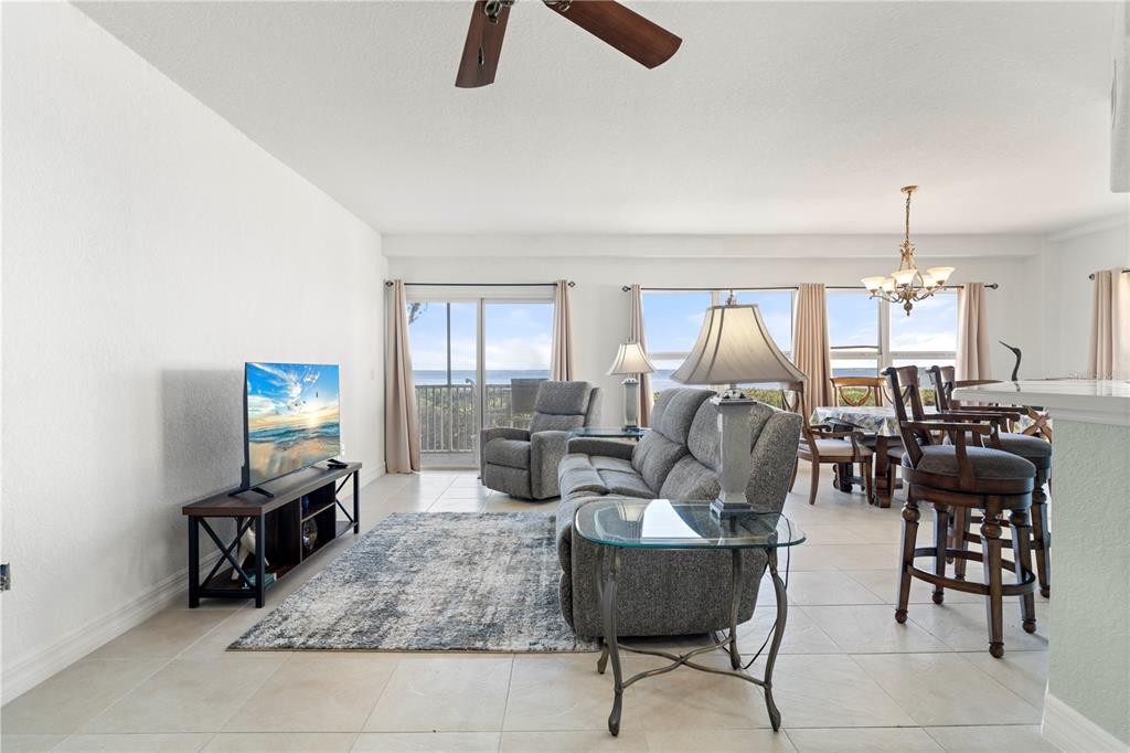 A living room features a gray sofa, a television, and a balcony with ocean views — 101 N MARION COURT UNIT 114, PUNTA GORDA, FL