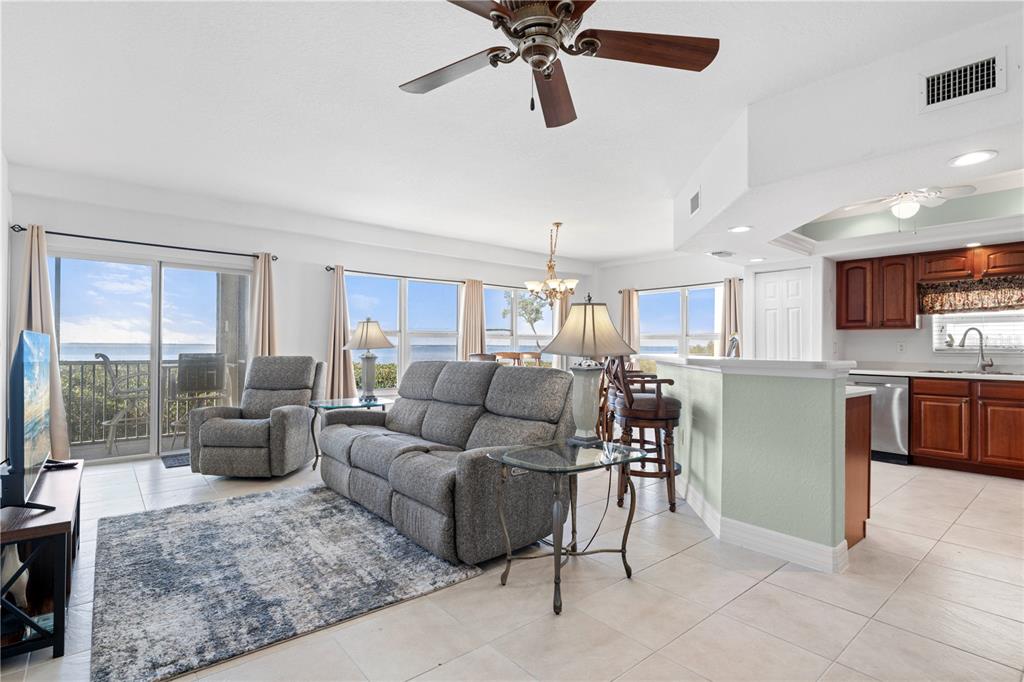 An open-concept living area features a gray sofa, tile flooring, and a kitchen with cabinets — 101 N MARION COURT UNIT 114, PUNTA GORDA, FL