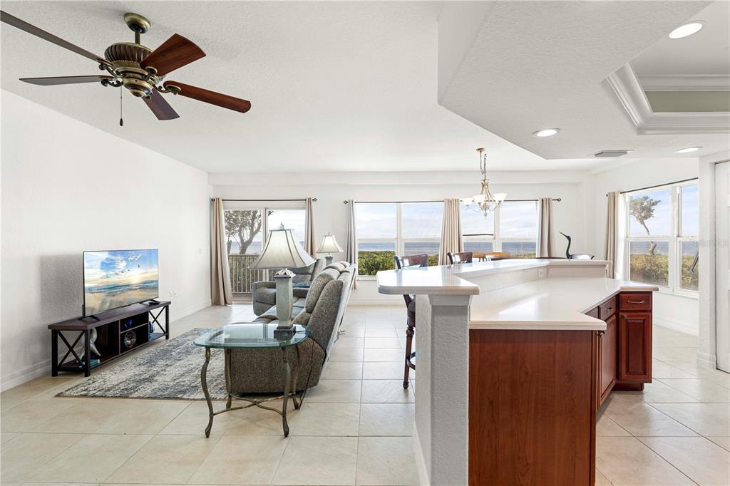 An open-concept living and dining area features tile floors, a kitchen island, and water views — 101 N MARION COURT UNIT 114, PUNTA GORDA, FL