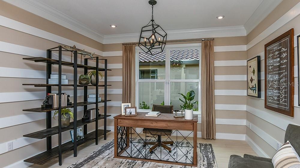 A home office features horizontal striped walls, a wooden desk, a metal bookshelf, and a chandelier — 3912 MASANIELLO WAY, WESLEY CHAPEL, FL