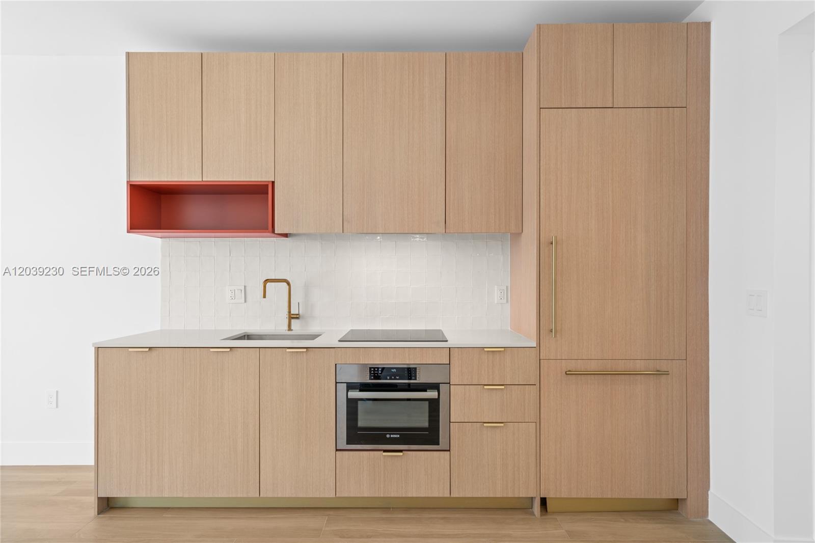 A modern kitchen features light wood cabinetry, a red open shelf, and gold hardware — 90 NE 32nd St # 1009, Miami FL 33127, MIAMI, FL