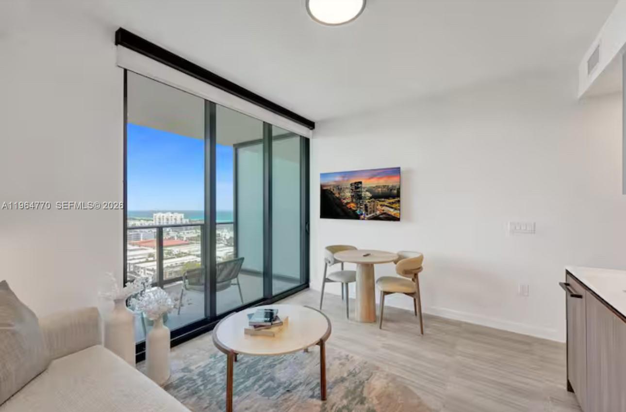 A living room with a dining area, floor-to-ceiling windows, and a balcony overlooking the ocean — 580 72 # 1713, Miami Beach FL 33141, MIAMI BEACH, FL
