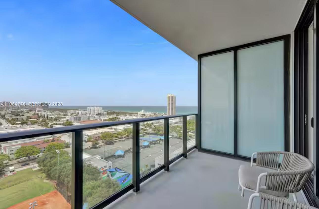 A balcony with a glass railing overlooks a coastal city and the ocean — 580 72 # 1713, Miami Beach FL 33141, MIAMI BEACH, FL
