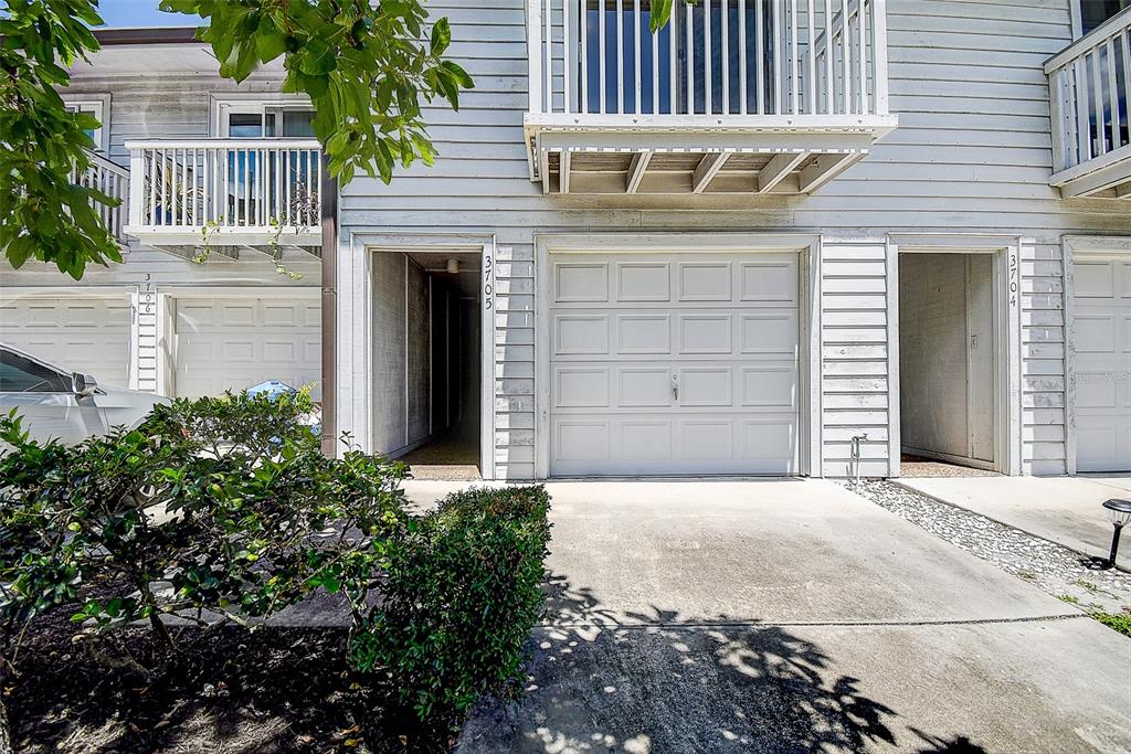 A two-story townhouse exterior features white horizontal siding, two garage doors, and small upper-level balconies — 6204 92ND PLACE N UNIT 3705, PINELLAS PARK, FL