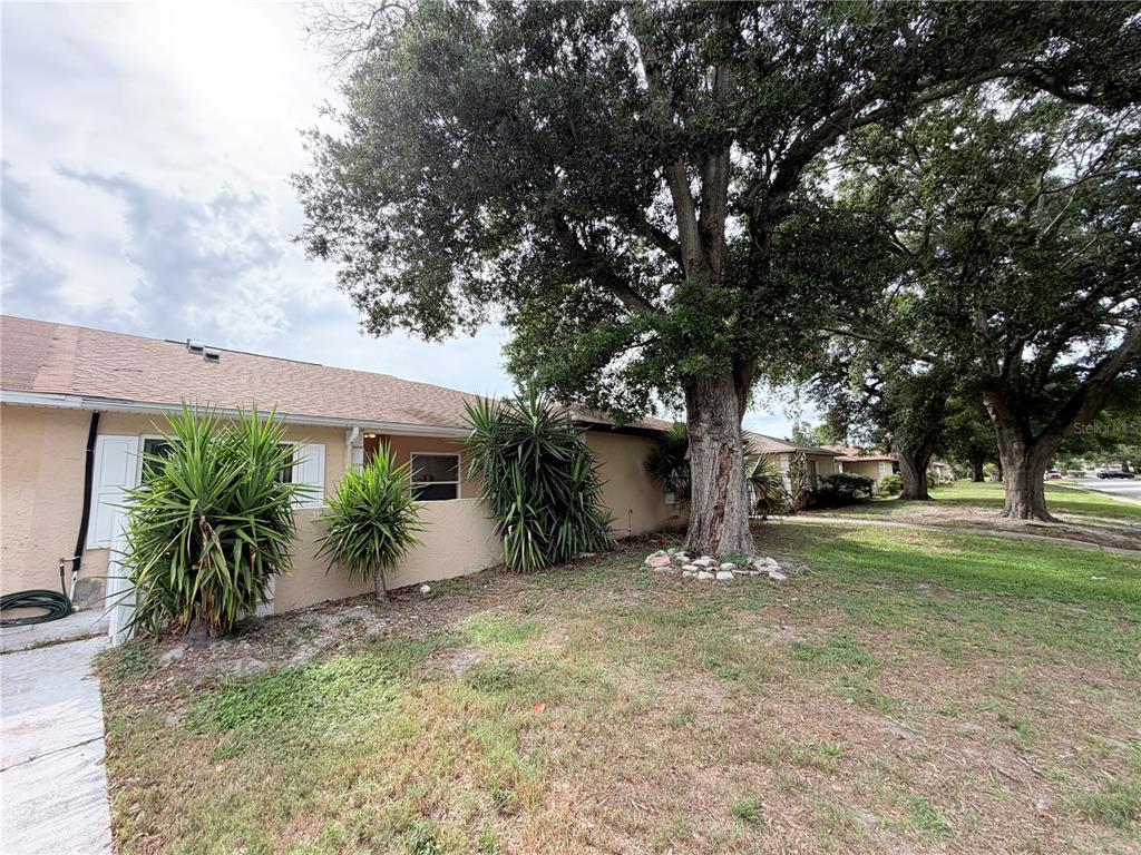 A single-story house with a tan exterior, a shingled roof, and large trees in front — 1128 SOPHIE BOULEVARD, ORLANDO, FL