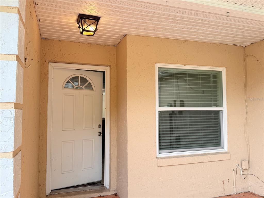 A tan stucco exterior wall features a white front door and a single window — 1128 SOPHIE BOULEVARD, ORLANDO, FL