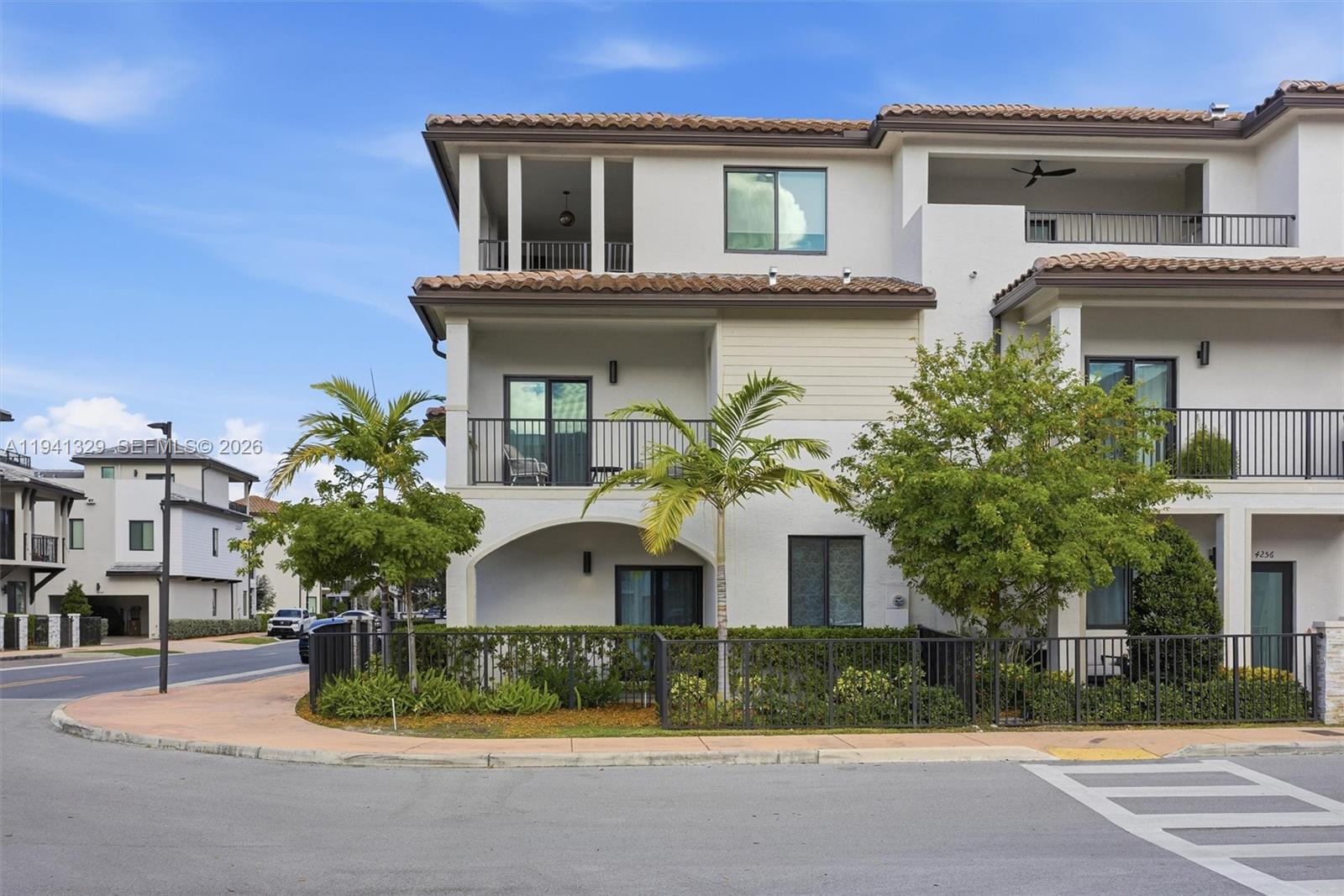 A three-story townhouse exterior features balconies, a fenced patio, and palm trees — 4250 NW 83rd Ave, Doral FL 33166, DORAL, FL