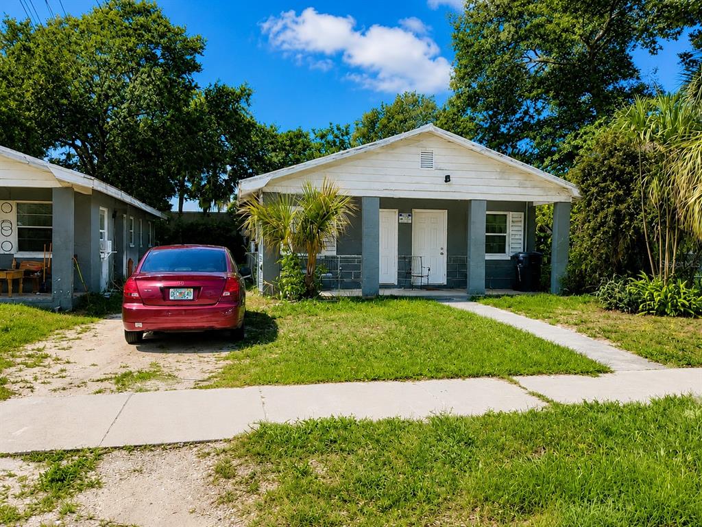 A red sedan is parked in front of a single-story house with a covered porch — 1506 N MADISON AVENUE, CLEARWATER, FL